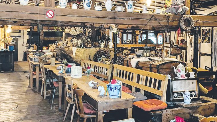 Innenraum des Restaurants mit Holztischen- und Stühlen geschmückt mit alten Teekannen- und Tassen