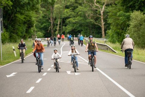 Een groep mensen fietst op een rustige straat. Kinderen en volwassenen genieten van een actieve dag in de natuur.