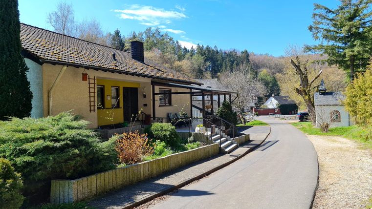 A quiet village with a cozy house and a paved street. Surrounded by trees and a well-kept landscape.