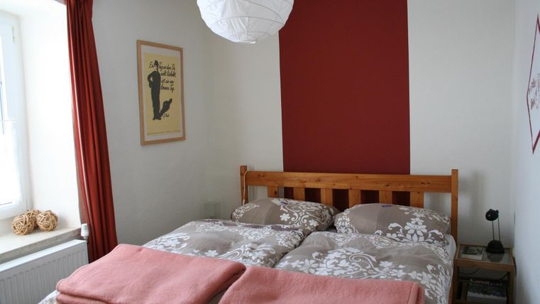 Een knusse slaapkamer met een tweepersoonsbed en een warme kleurstelling. De ruimte heeft natuurlijke lichtbronnen en decoratieve elementen.