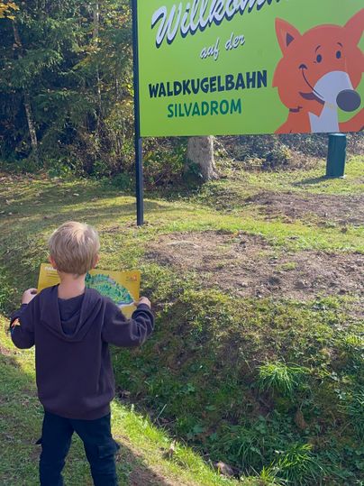 Ein Junge steht vor der Starttafel der Waldkugelbahn in Gerolstein