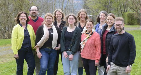 Zehn Personen stehen dicht beieinander und lächeln in die Kamera.