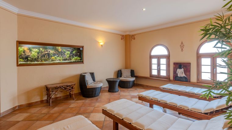 Ein entspannender Ruheraum mit Liegen, einem Aquarienblick und warmem Licht. Der Raum ist gemütlich und lädt zur Erholung ein.