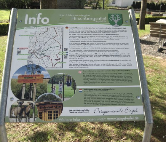 Informationstafel zum Hirschbergsattel in Birgel mit Wanderkarte, Bildern von Ziegen, einem Spielplatz und der Bielenhof-Alm., © Touristik GmbH Gerolsteiner Land