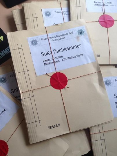 Beige Akten mit rotem Siegel und der Aufschrift 'SoKo Dachkammer', datiert auf den 29.9.1978, liegen gestapelt auf einem Tisch.