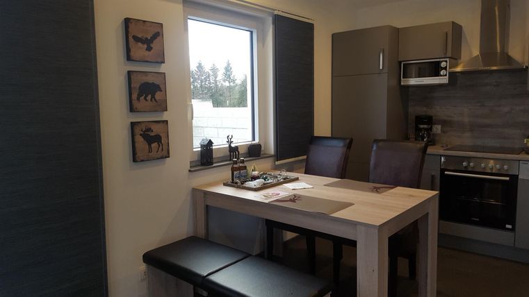 Ein gemütlicher Essbereich mit einem Tisch und Stühlen. An der Wand hängen dekorative Holztafelbilder von Tieren.