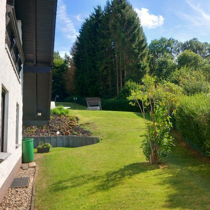 Ein weitläufiger und gepflegter Garten mit Sitzgelegenheit