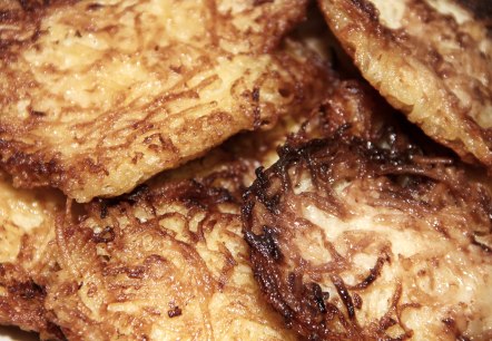 Close-up of several stacked potato pancakes glistening with grease.