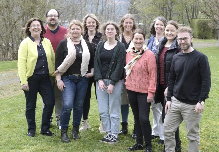 Ten people stand close together and smile for the camera.
