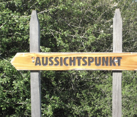 Holzschild mit der Aufschrift 'Aussichtspunkt' vor dichtem grünen Gebüsch., © Touristik GmbH Gerolsteiner Land