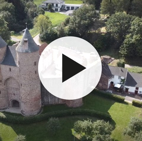 Aerial view of Bertrada Castle in Mürlenbach with video play button in the foreground.