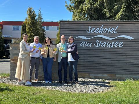 Fünf Personen stehen vor der Fassade des Seehotels am Stausee in gerolstein und halten jeweils 4 Sterne und ein "S" für die Sterneklassifizierung hoch.