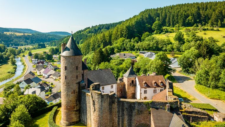 seitliche Luftaufnahme der Bertradaburg mit einer grünen Landschaft herum. Teile des Dorfes sind auch zu erkennen.