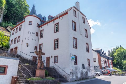 Historisches Gebäude in Gerolstein mit der Aufschrift 'Anno 1710' und '1949', Treppen und Statue im Vordergrund, blauer Himmel im Hintergrund.