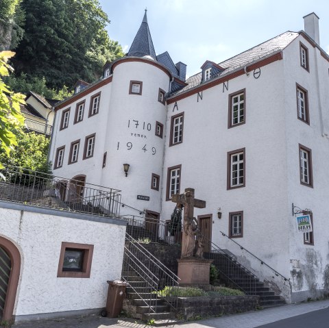 Historic building in Gerolstein with the inscriptions &ldquo;Anno 1710&rdquo; and &ldquo;1949&rdquo;, stairs and statue in the foreground, blue sky in the background.