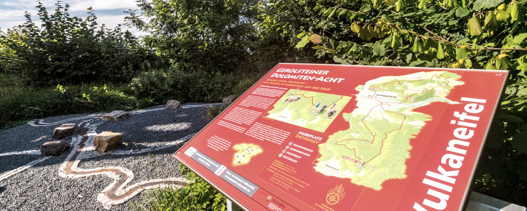 Informatiebord bij de Mu&szlig;eplatz aan de Dietzenley in het Keltenpfad, omgeven door bomen en een heldere hemel.