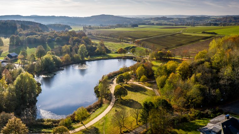 Landschaft mit See, umgeben von Bäumen und Feldern, im Bolsdorfer Tälchen, Hillesheim.