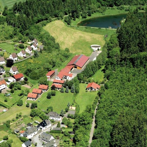 Luftaufnahme von J&uuml;nkerath und des Ferienhof Kloep zwischen neben einem dichten Wald und Blick auf den Stausee J&uuml;nkerath.