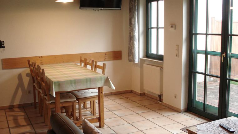 Een lichte slaapkamer met een grote eettafel en stoelen. Grote ramen bieden uitzicht naar buiten.