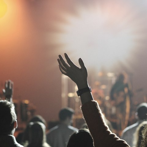 Several arms and heads looking towards a stage at a live concert