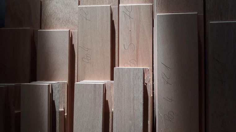 Eine Ansammlung von hellen Holzstücken in verschiedenen Höhen. Das Licht fällt sanft auf die Oberfläche und erzeugt Schatten.