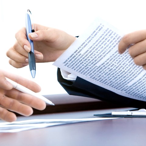Close-up of hands of two people holding notes and pens