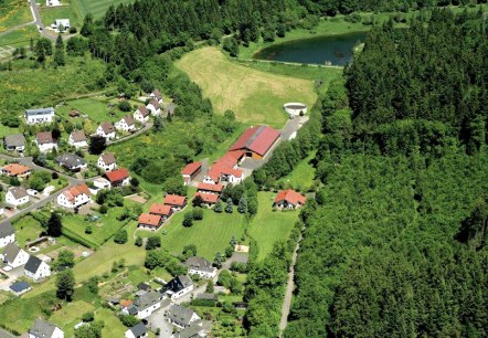 Aerial view of J&uuml;nkerath and the Kloep holiday farm between a dense forest and a view of the J&uuml;nkerath reservoir.