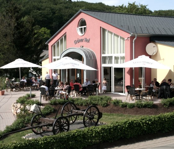 Exterior fa&ccedil;ade of the restaurant building at Gr&ouml;ner Hof with numerous visitors seated at tables and under parasols on the terrace.