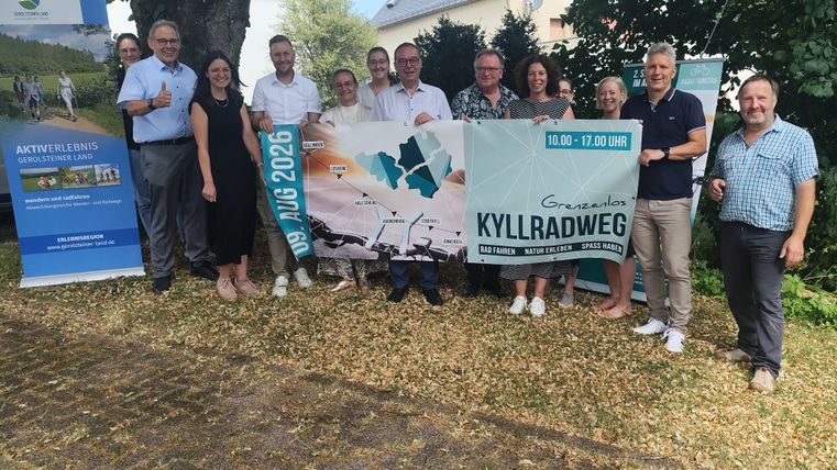 Eine Gruppe Menschen halten gemeinsam einen Veranstaltungsbanner zum Radaktionstag Grenzenlos Kyllradweg 2026 hoch.