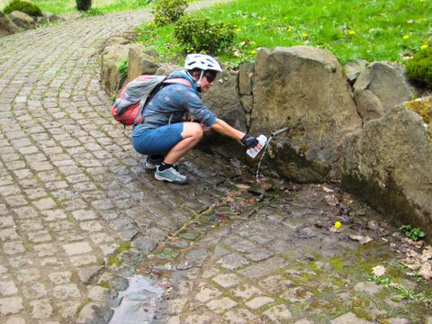 Radfahrer an der Quelle, der seine Flasche füllt