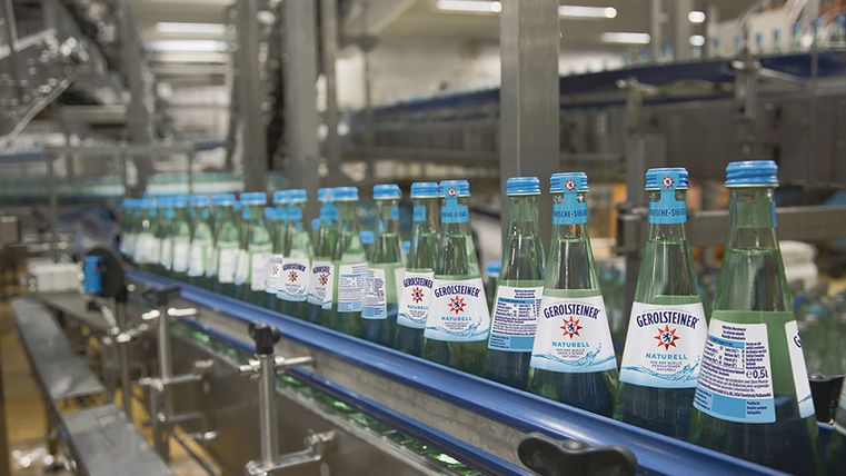 Fließband mit zahlreichen Wasserflaschen der Marke Gerolsteiner und Abfüllanlage.