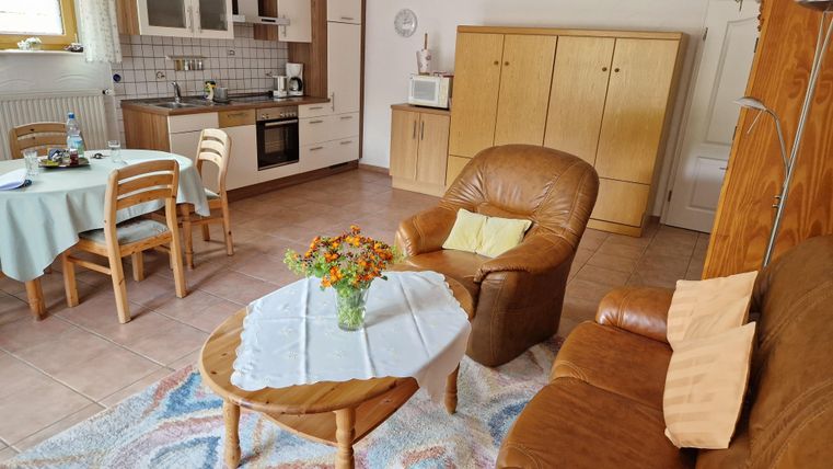 Wohn- und Esszimmer mit einem braunen Sofa und einer Küche im Hintergrund