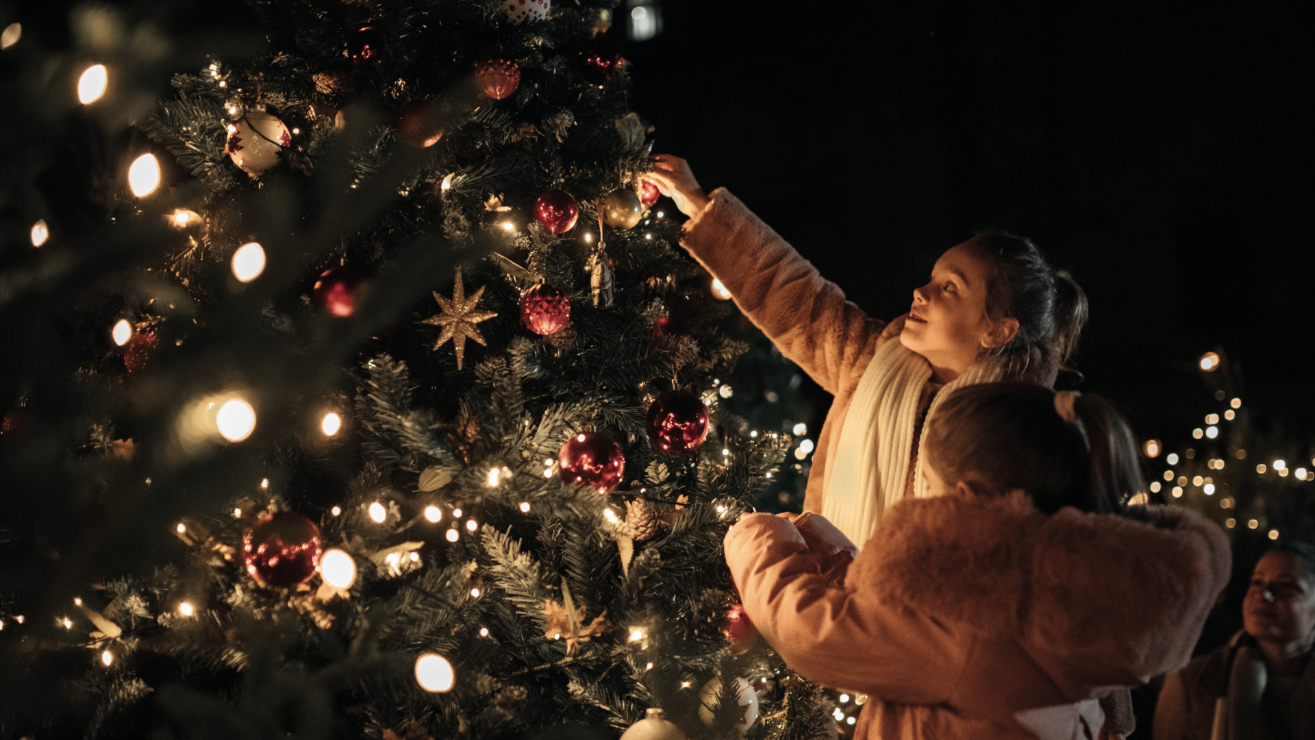 zwei Kinder schmücken einen Weihnachtsbaum mit Kugeln. Der baum leuchtet schon in der Dunkelheit, © Touristik GmbH Gerolsteiner Land