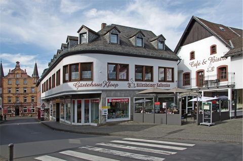 Ein charmantes Gebäude mit einem Café und Bistro in einer Stadt. Die Umgebung ist einladend mit einer Fußgängerzone.