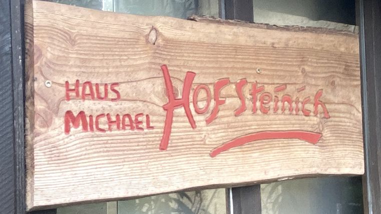 Holzschild mit Aufschrift "Haus Micheal Hof Steinich an einer Fensterscheibe.