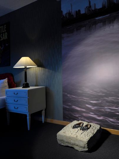 Une chambre élégante avec une lampe, une table de nuit et un tapis chic. Le mur présente une image abstraite sombre d'une surface d'eau.
