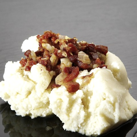 A pile of mashed potatoes topped with diced bacon and onions.