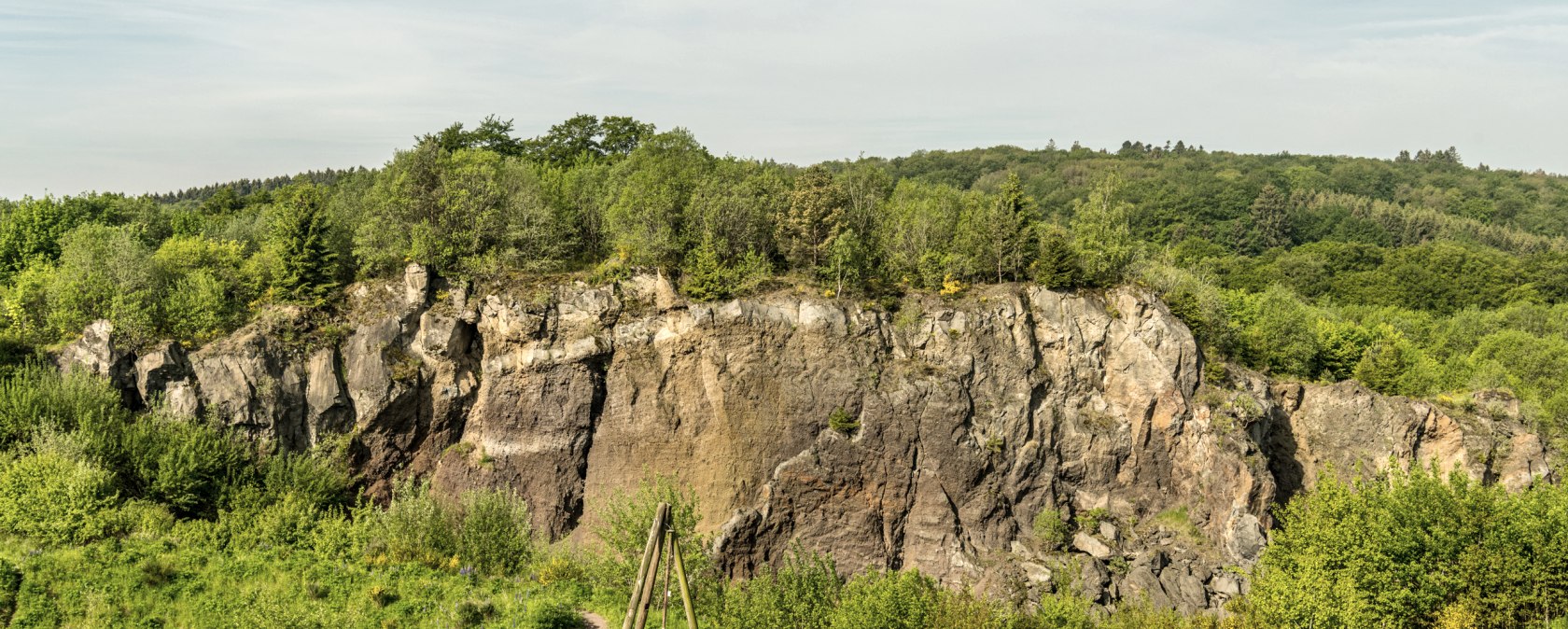 Rocky volcanic wall in a green landscape.