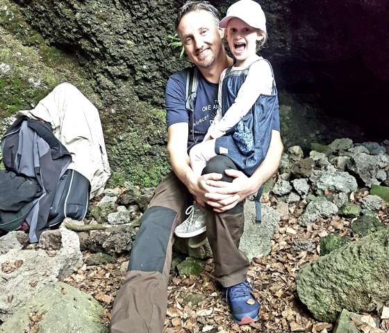 Vater mit Tochter auf dem Schoß sitze in einer Höhle