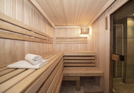 A small sauna room with a wooden bench and a glass front.