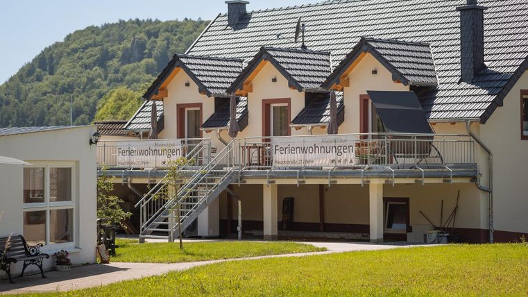 Ein modernes Ferienhaus mit einem geschmackvollen Balkon. Umgeben von grünen Hügeln bietet es eine einladende Atmosphäre.