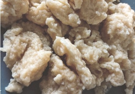 Mehrere unterschiedlich geformte Teigknödel liegen aufeinander in einer Schale.