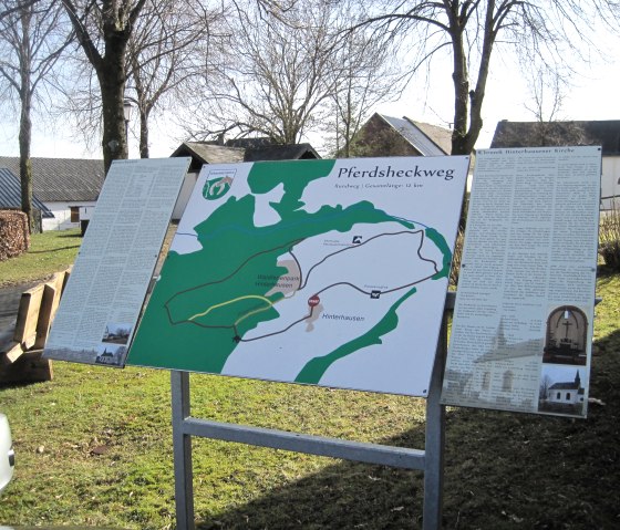Horse trail information board with map and texts, set up outdoors in sunny weather. Trees and buildings can be seen in the background., © Touristik GmbH Gerolsteiner Land, Ute Klinkhammer