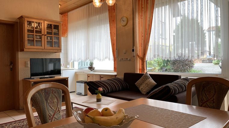 Ein gemütlicher Wohnraum mit einem Esstisch und einer Fruit Bowl. Große Fenster sorgen für viel Tageslicht und Blick ins Freie.