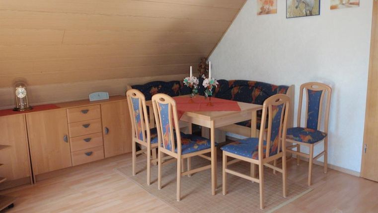 Ein gemütlicher Essbereich mit einem Holztisch und sechs Stühlen. Der Raum hat eine helle Atmosphäre und ist mit Dekorationen an den Wänden geschmückt.