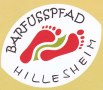 Logo van het blotevoetenpad Hillesheim met rode voetafdrukken en een groene streep op een witte achtergrond., © Parklandschaft mit Bäumen und einer saftigen Wiese an einem Fußweg neben einem See.