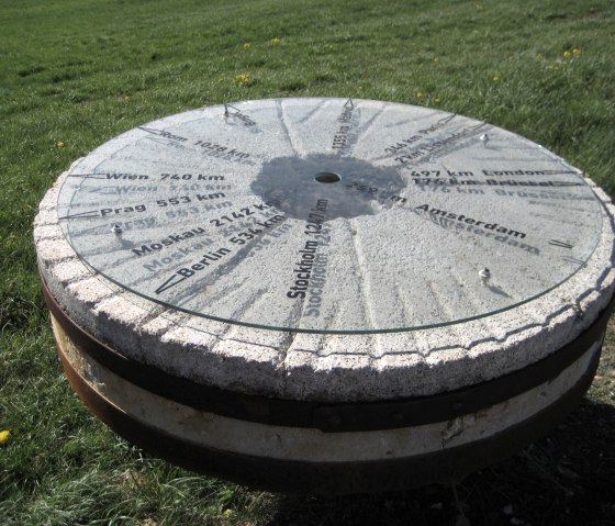 A millstone on a meadow shows distances to cities such as Vienna, Prague and Moscow., © Touristik GmbH Gerolsteiner Land