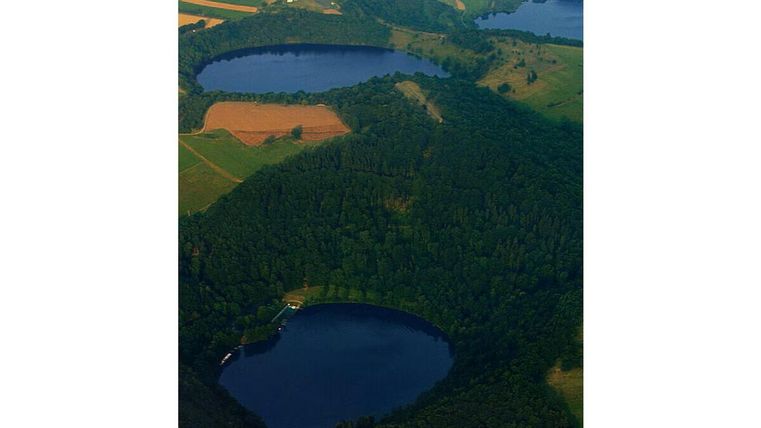 Eine Luftaufnahme von mehreren Seen, umgeben von dichten Wäldern und Feldern. Die Landschaft ist grün und vielfältig.