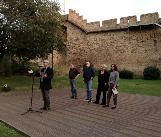 F&uuml;nf Personen auf einer Flachen Freilichtb&uuml;hne vor der Hillesheimer Stadtmauer