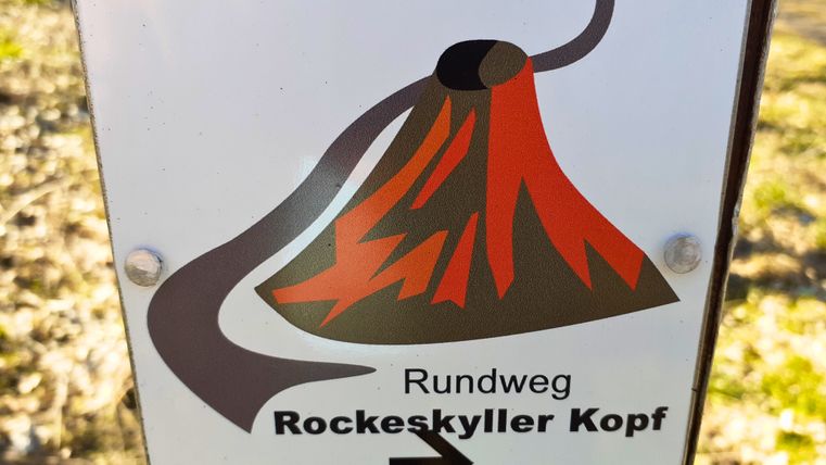 Wanderweg-Schild mit Vulkan-Symbol und Text 'Rundweg Rockeskyller Kopf'.